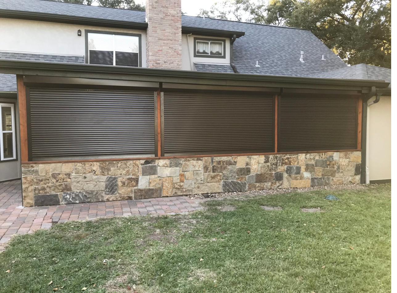 Bronze roll-down shutters integrated into a residential stone facade