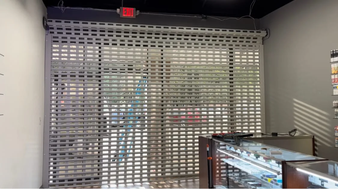 Perforated TMAX roll-down shutter protecting an interior retail opening